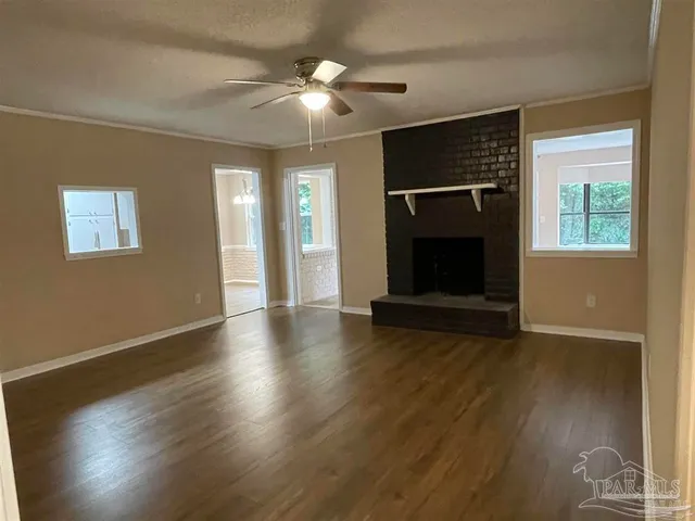 an empty room with wooden floor fireplace and windows