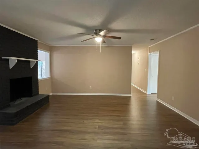 a view of an empty room with wooden floor and a fireplace