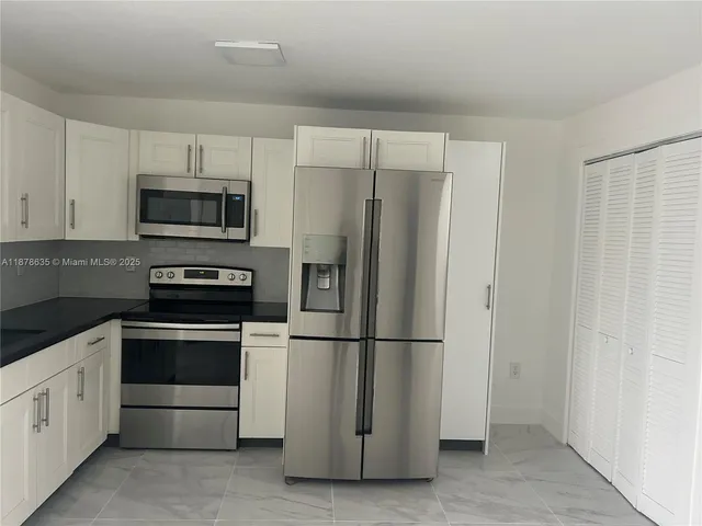 a kitchen with granite countertop white cabinets and stainless steel appliances