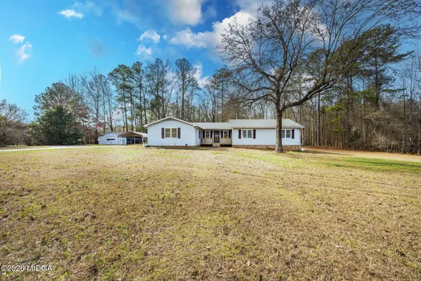 a view of house with outdoor space and trees in the background
