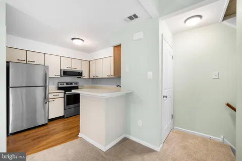 a kitchen with a refrigerator a stove top oven and cabinets