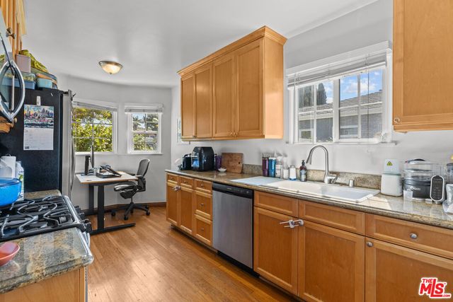 a kitchen with stainless steel appliances granite countertop a stove a sink dishwasher and cabinets with wooden floor