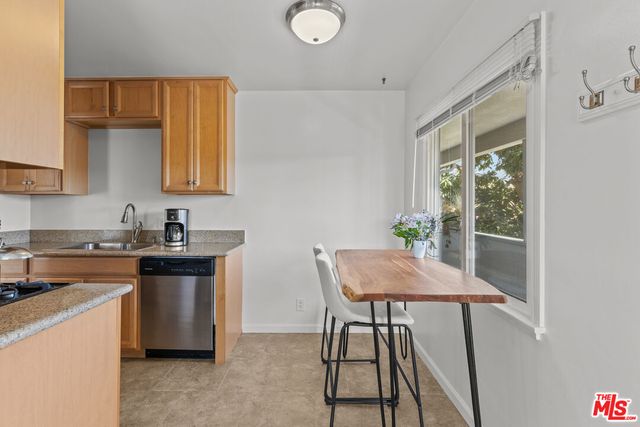 a kitchen with stainless steel appliances granite countertop a stove a sink dishwasher and white cabinets with wooden floor