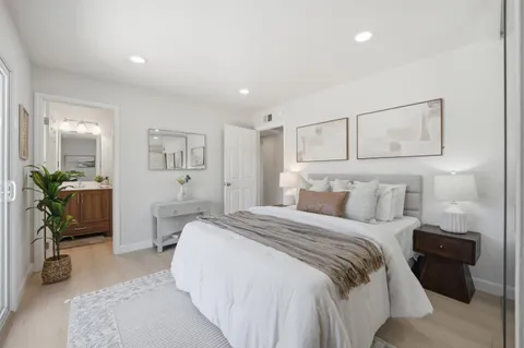 a bedroom with a bed a couch and potted plant with the dresser