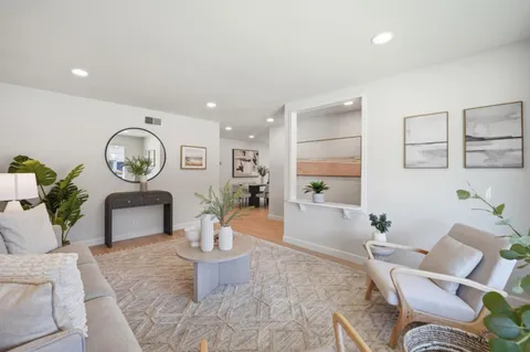 a living room with furniture a large window and a potted plant