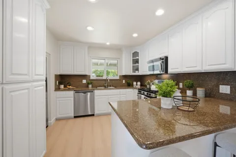 a kitchen with stainless steel appliances granite countertop a sink refrigerator and cabinets