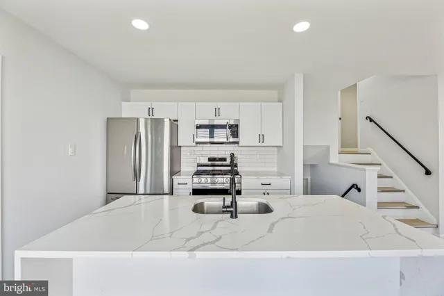a kitchen with kitchen island a stove a refrigerator and a sink with wooden floor