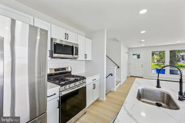 a kitchen with granite countertop a sink stainless steel appliances and cabinets