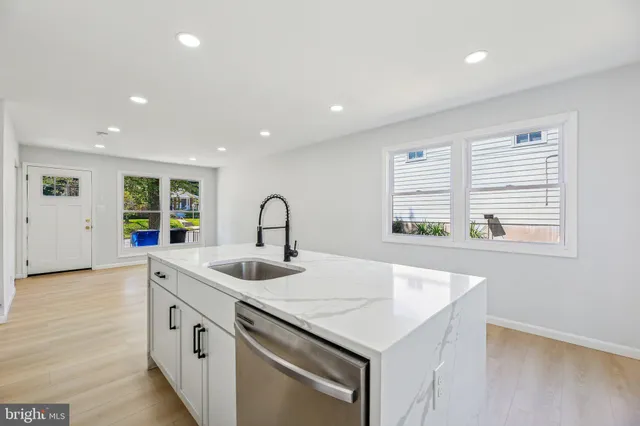 a kitchen that has a sink a stove and a window with wooden floor