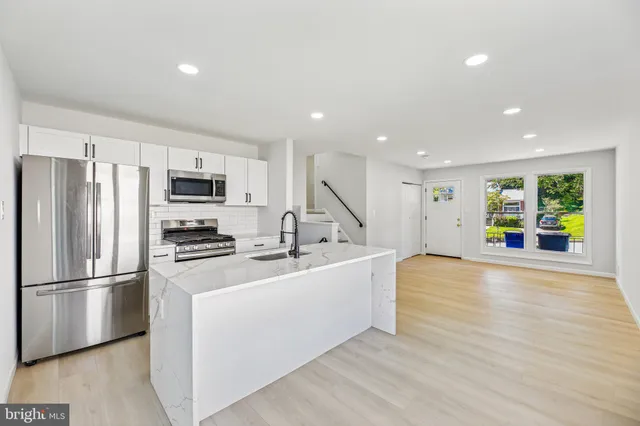 a large kitchen with stainless steel appliances a large counter top and wooden floors