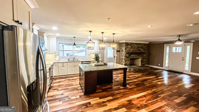 a view of a kitchen with stainless steel appliances kitchen island granite countertop a refrigerator and a stove top oven