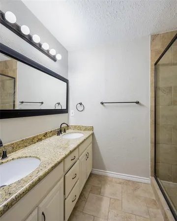 a bathroom with a granite countertop sink a mirror and a shower