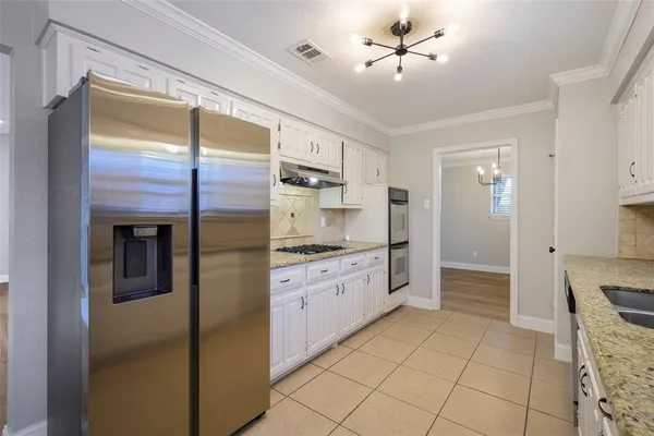a kitchen with stainless steel appliances granite countertop a refrigerator and a stove top oven