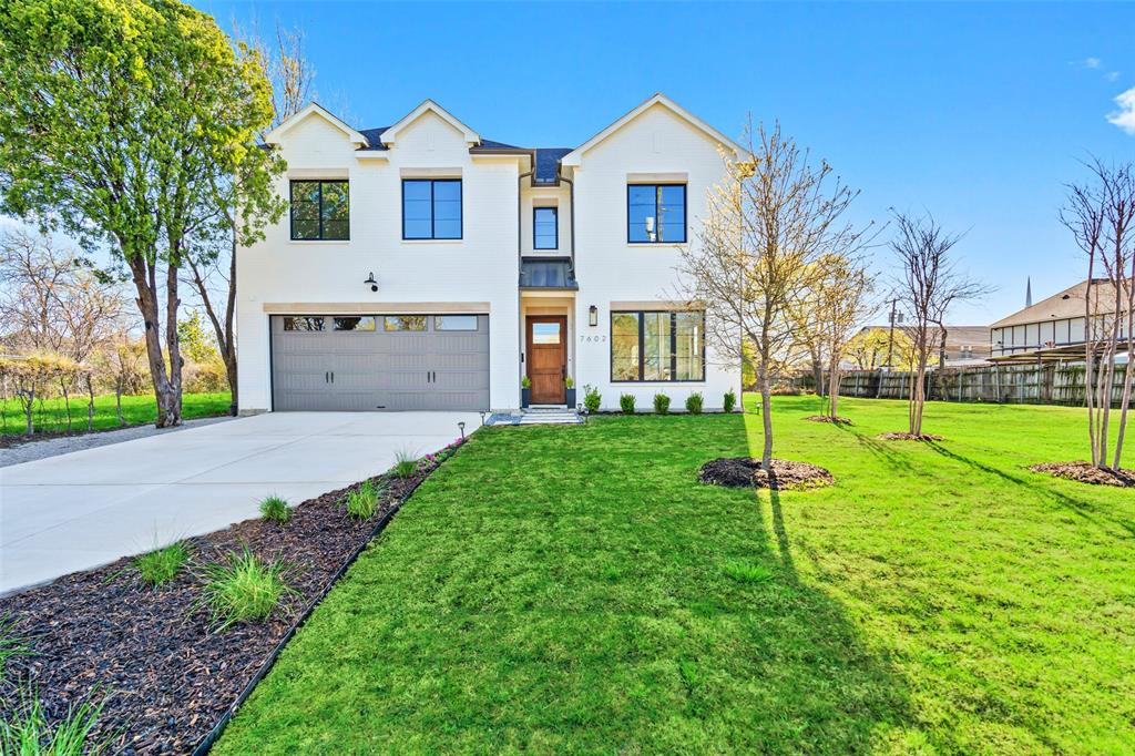a front view of a house with a yard and trees