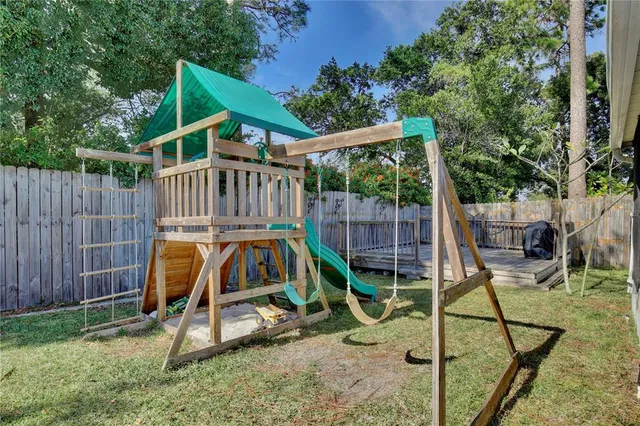 a view of a backyard with a slide trees and wooden fence