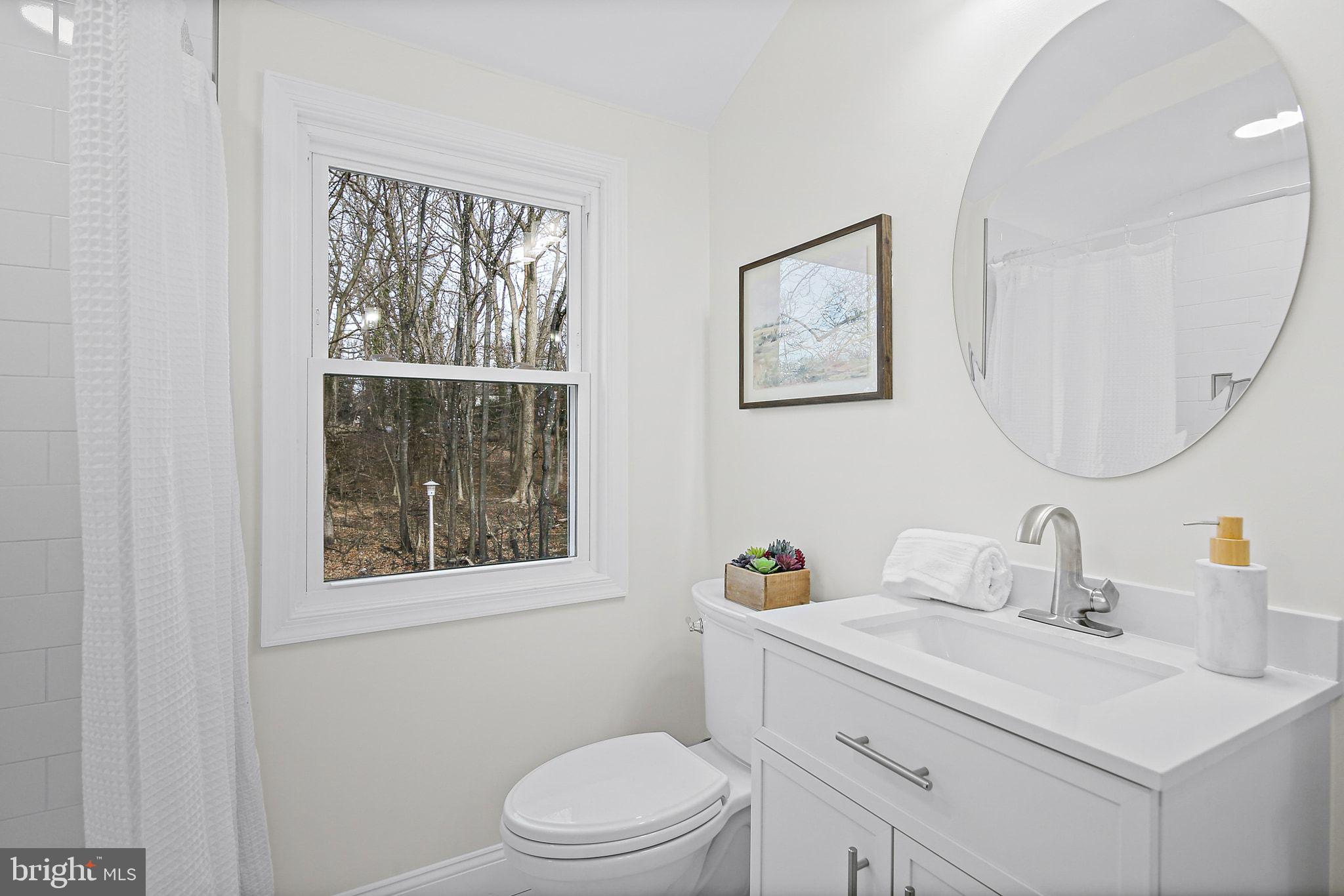 402 Westgate Road Baltimore, MD 21229 - Photo 23 of 37 a bathroom with a toilet a sink a mirror and a window