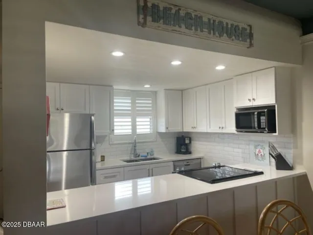 a kitchen with stainless steel appliances granite countertop a refrigerator a stove a sink and a microwave