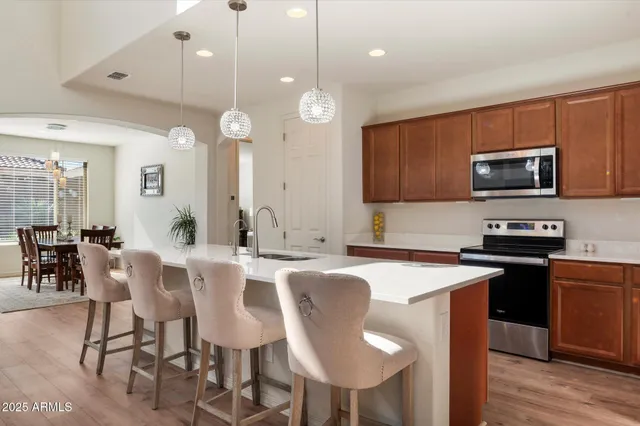 a kitchen with stainless steel appliances granite countertop a sink a stove a dining table and chairs
