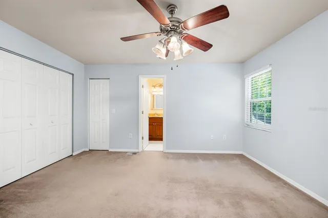 an empty room with a window and a chandelier fan