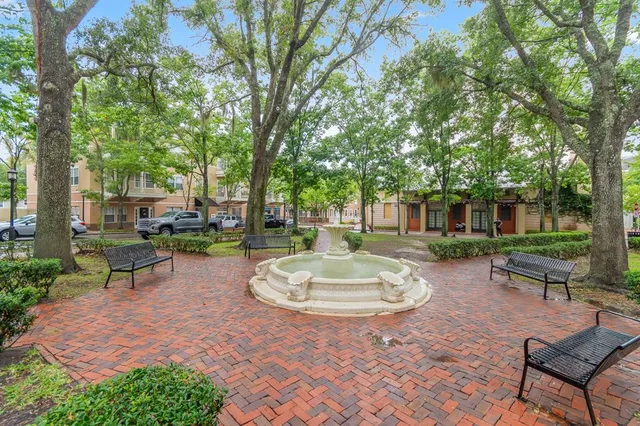 a view of a backyard with table and chairs potted plants and large tree