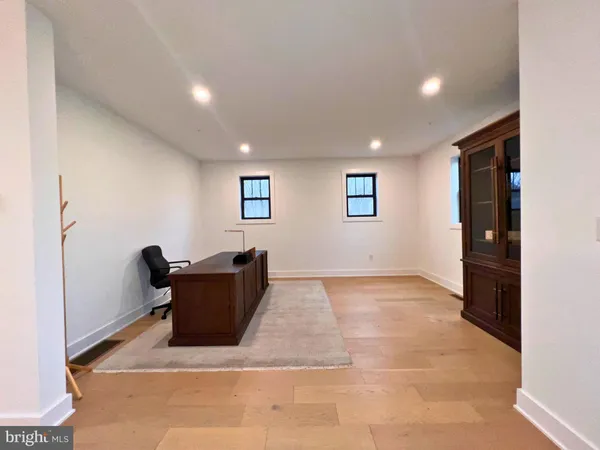 a view of a hallway to a room with wooden floor and windows