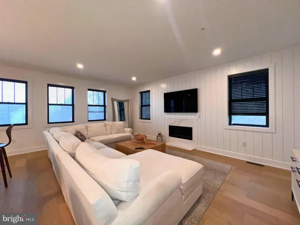 a large white kitchen with a stove a sink a dining table chairs and couches