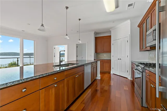 a large kitchen with stainless steel appliances granite countertop a stove a sink a refrigerator and a wooden cabinets