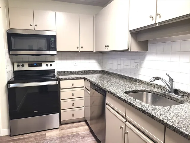 a kitchen with granite countertop a stove microwave and sink