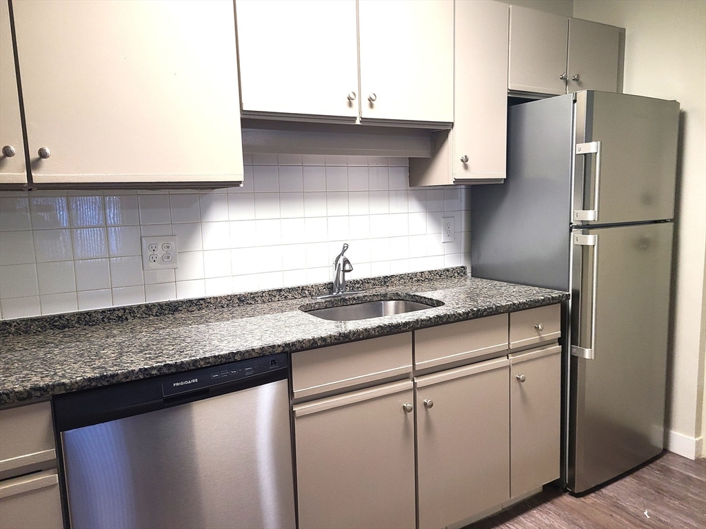 576 Washington Street, Unit 114 Weymouth, MA 02188 - Photo 12 of 24 a kitchen with granite countertop a sink cabinets and stainless steel appliances