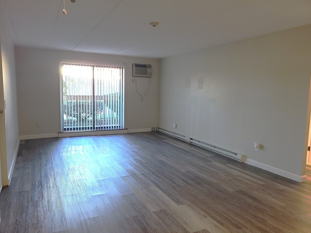 576 Washington Street, Unit 114 Weymouth, MA 02188 - Photo 3 of 24 an empty room with wooden floor and windows