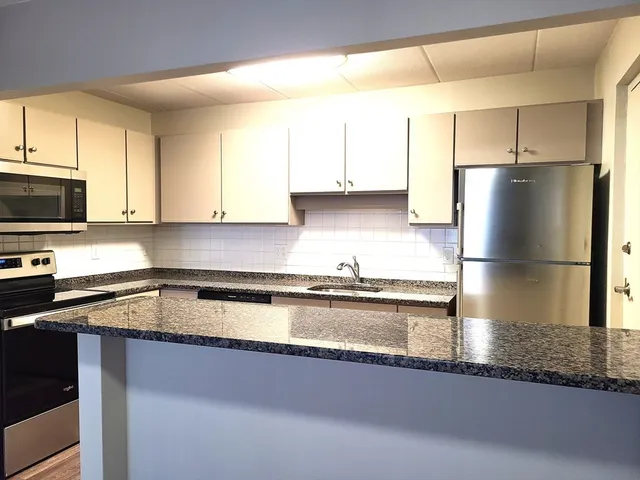 a kitchen with stainless steel appliances granite countertop a sink a refrigerator and a granite counter tops