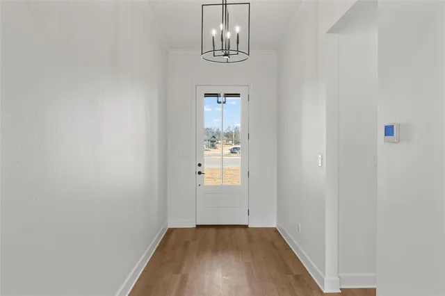 a view of a hallway with wooden floor and chandelier