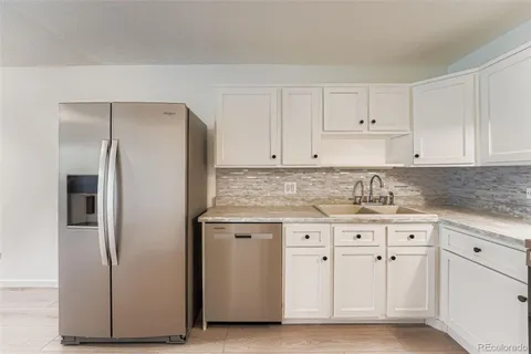 a kitchen with white cabinets and refrigerator