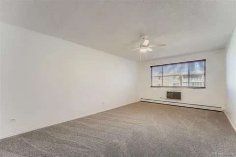 an empty room with chandelier fan and windows