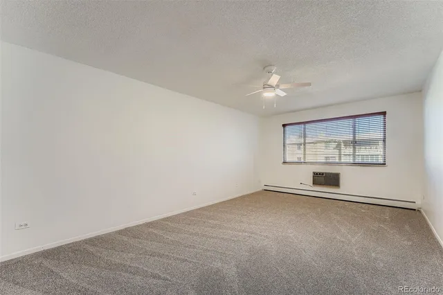 an empty room with chandelier fan and windows