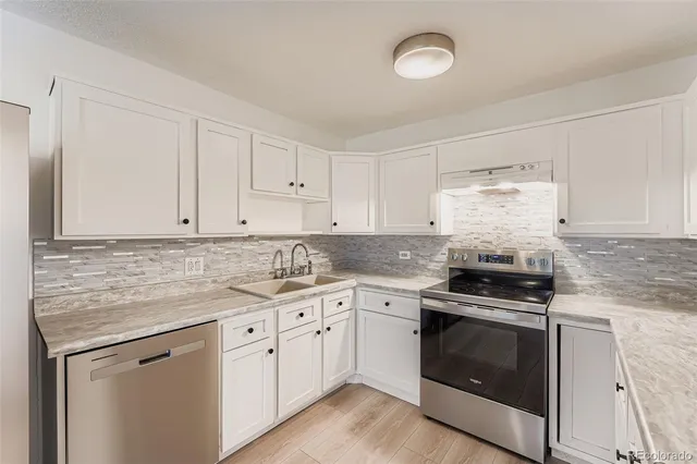 a kitchen with granite countertop white cabinets and stainless steel appliances