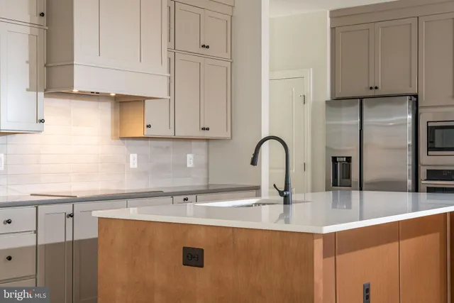 a kitchen with stainless steel appliances granite countertop a sink a stove and a refrigerator with wooden cabinets