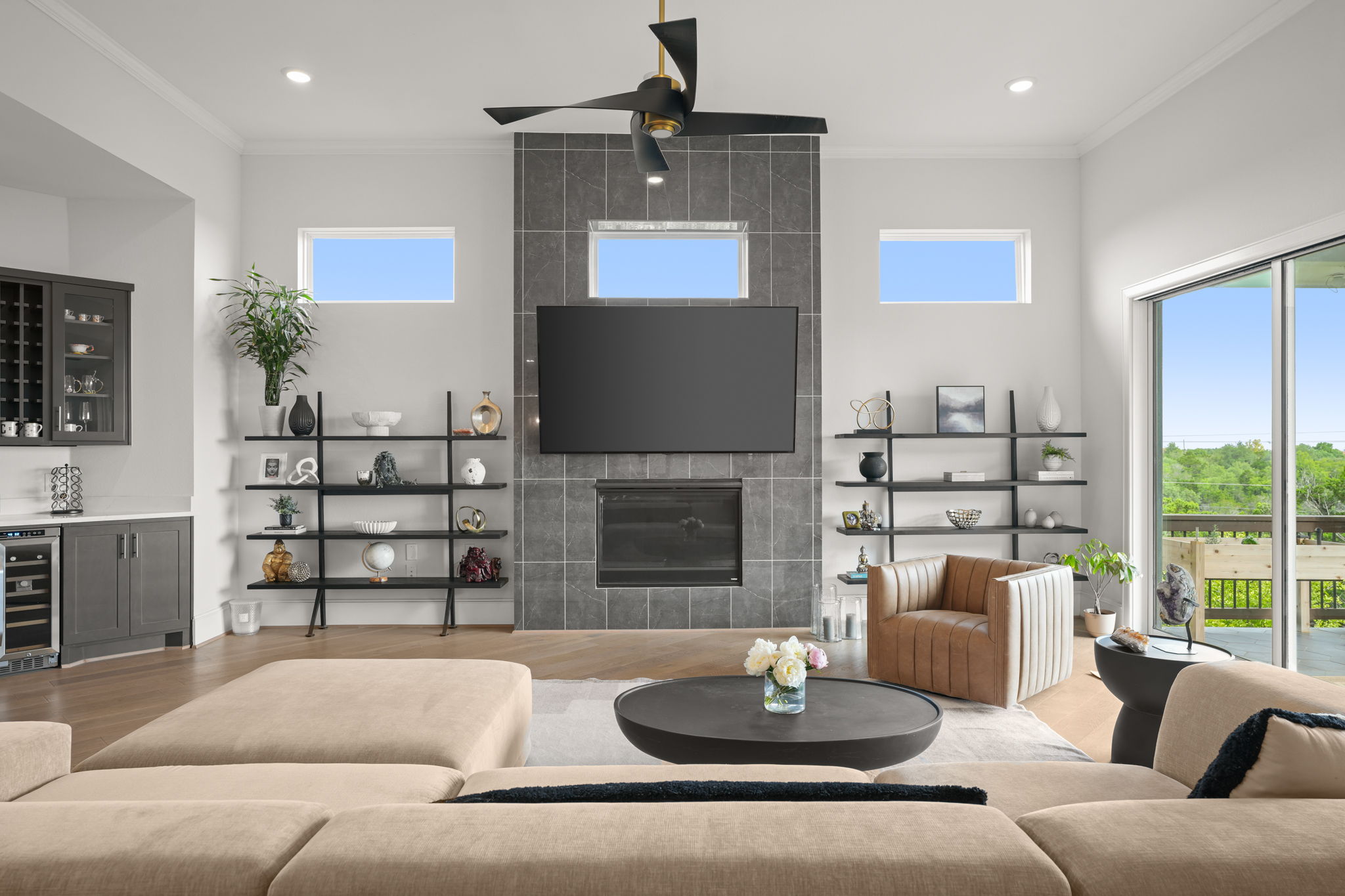 104 Lodestone Cove Austin, TX 78738 - Photo 12 of 40 A refined living area showcases a sleek fireplace beneath a large television, flanked by open shelving and bright windows.