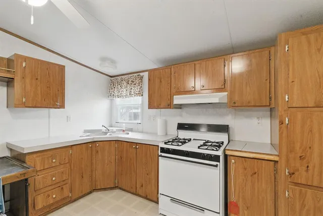 an empty room with a kitchen and a chandelier fan
