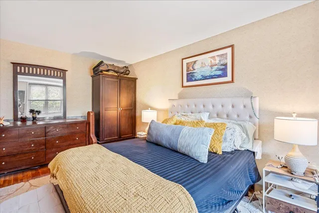 a bedroom with a bed painting on wall and a dresser