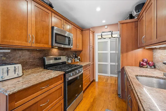 a kitchen with stainless steel appliances granite countertop a stove a sink and a microwave