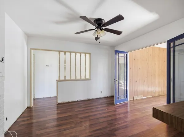 a view of an empty room with wooden floor and a window