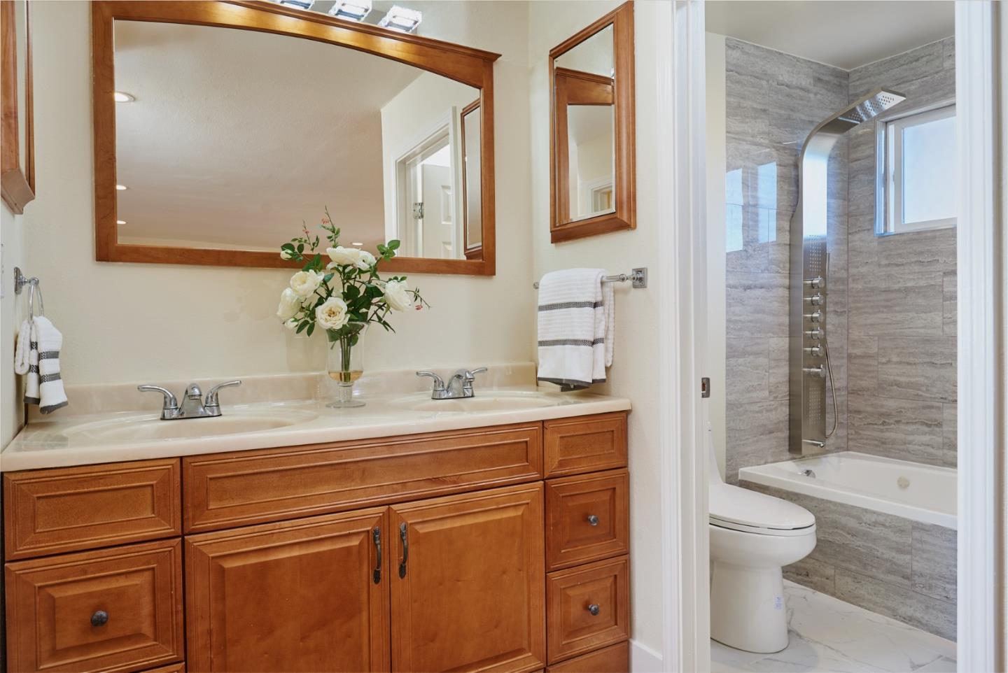 1132 Lassen Drive Belmont, CA 94002 - Photo 17 of 27 a bathroom with a granite countertop sink toilet mirror and shower