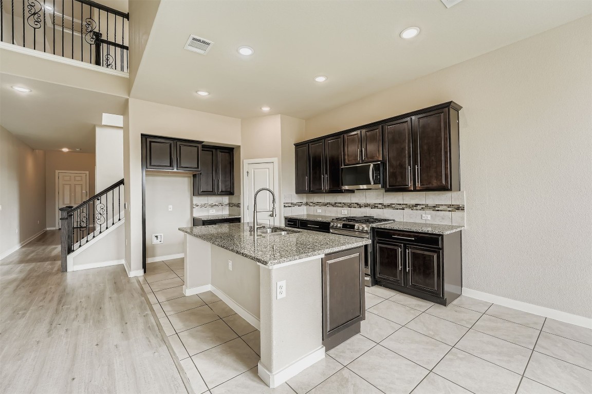 11209 American Mustang Loop Manor, TX 78653 - Photo 13 of 34 a kitchen with stainless steel appliances granite countertop a stove top oven a sink and a microwave