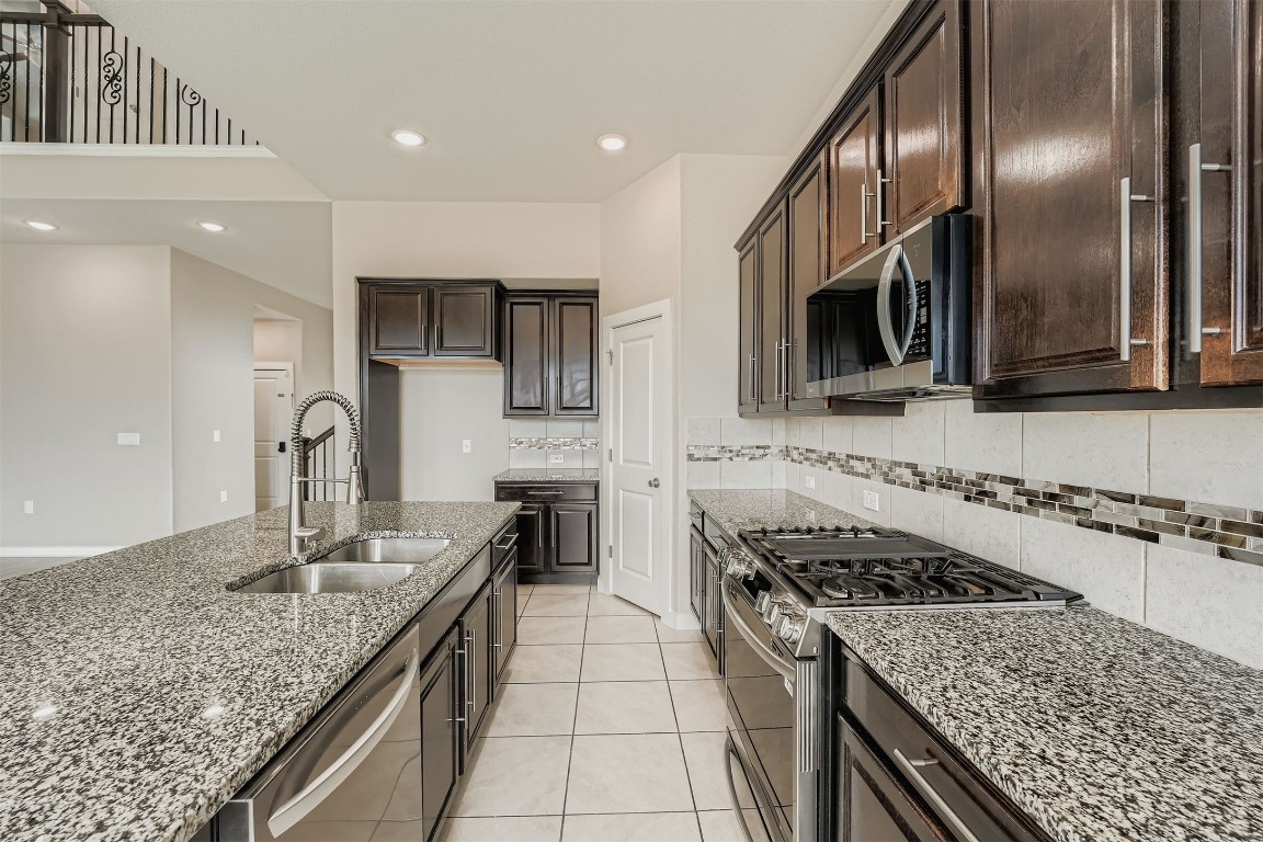 11209 American Mustang Loop Manor, TX 78653 - Photo 14 of 34 a kitchen with stainless steel appliances granite countertop a sink stove and cabinets