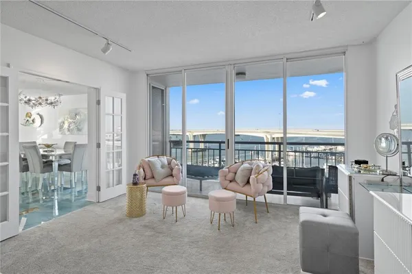 a living room with furniture large windows and wooden floor