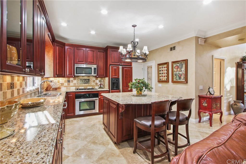 11610 Goetting Avenue Tustin, CA 92782 - Photo 18 of 62 a kitchen with stainless steel appliances granite countertop a stove top oven a sink dishwasher a dining table and chairs with wooden floor