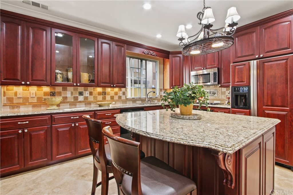 11610 Goetting Avenue Tustin, CA 92782 - Photo 19 of 62 a kitchen with kitchen island granite countertop wooden cabinets a refrigerator a sink dishwasher with a dining table and chairs