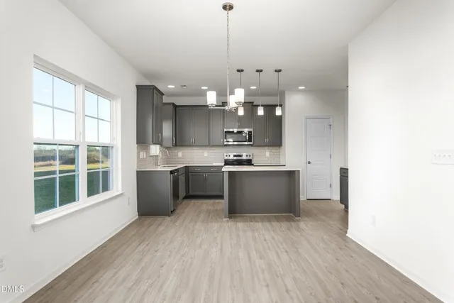 a large kitchen with kitchen island a large counter space a sink stainless steel appliances and cabinets