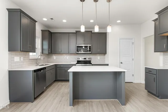 a kitchen with kitchen island a sink stainless steel appliances and cabinets